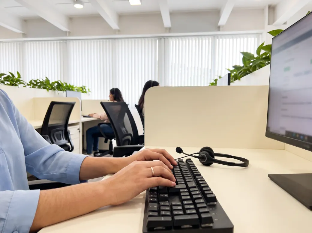 Manos escribiendo en un teclado junto a una diadema